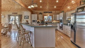 A cabin-style kitchen with a central island, wooden ceiling, and built-in appliances. - Carter`s Lake Overlook | Ellijay, Ga (Ellijay)