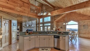 A spacious kitchen with a large island, wooden ceiling beams, and a view of the outdoors. - Carter`s Lake Overlook | Ellijay, Ga (Ellijay)