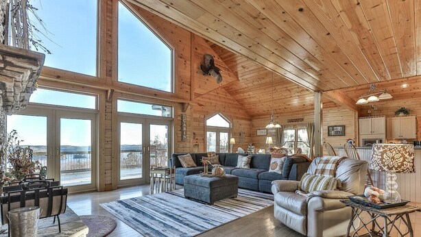 A spacious living room with a large sofa, a smaller sofa, and a coffee table. There are multiple windows allowing natural light and views of the outdoors. - Carter`s Lake Overlook | Ellijay, Ga (Ellijay)