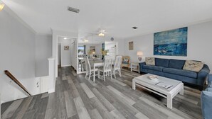 Un vaste espace de vie comprenant une table à manger et des chaises, un canapé bleu et un grand tableau accroché au mur.