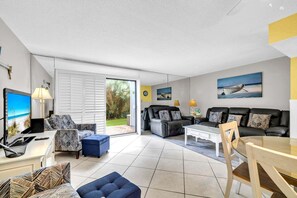 A modern living room with a sofa set, a coffee table, a TV, and a dining area.