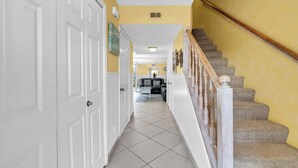 A hallway with a carpeted staircase, white doors, and a yellow wall. - Southbay by the Gulf 99 – Spacious Townhome with Private Beach Access (Destin)