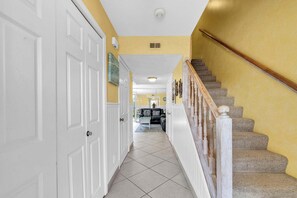 A hallway with a carpeted staircase, white doors, and a yellow wall. - Southbay by the Gulf 99 – Spacious Townhome with Private Beach Access (Destin)