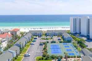 Ett hotell vid stranden med en tennisbana, parkering och utsikt över havet.