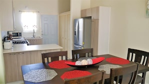 A compact kitchen with a microwave, toaster, and stove. There is a dining table with chairs and a decorative bowl. - Lux Sea View Camelot Village Discovery Bay (Discovery Bay)