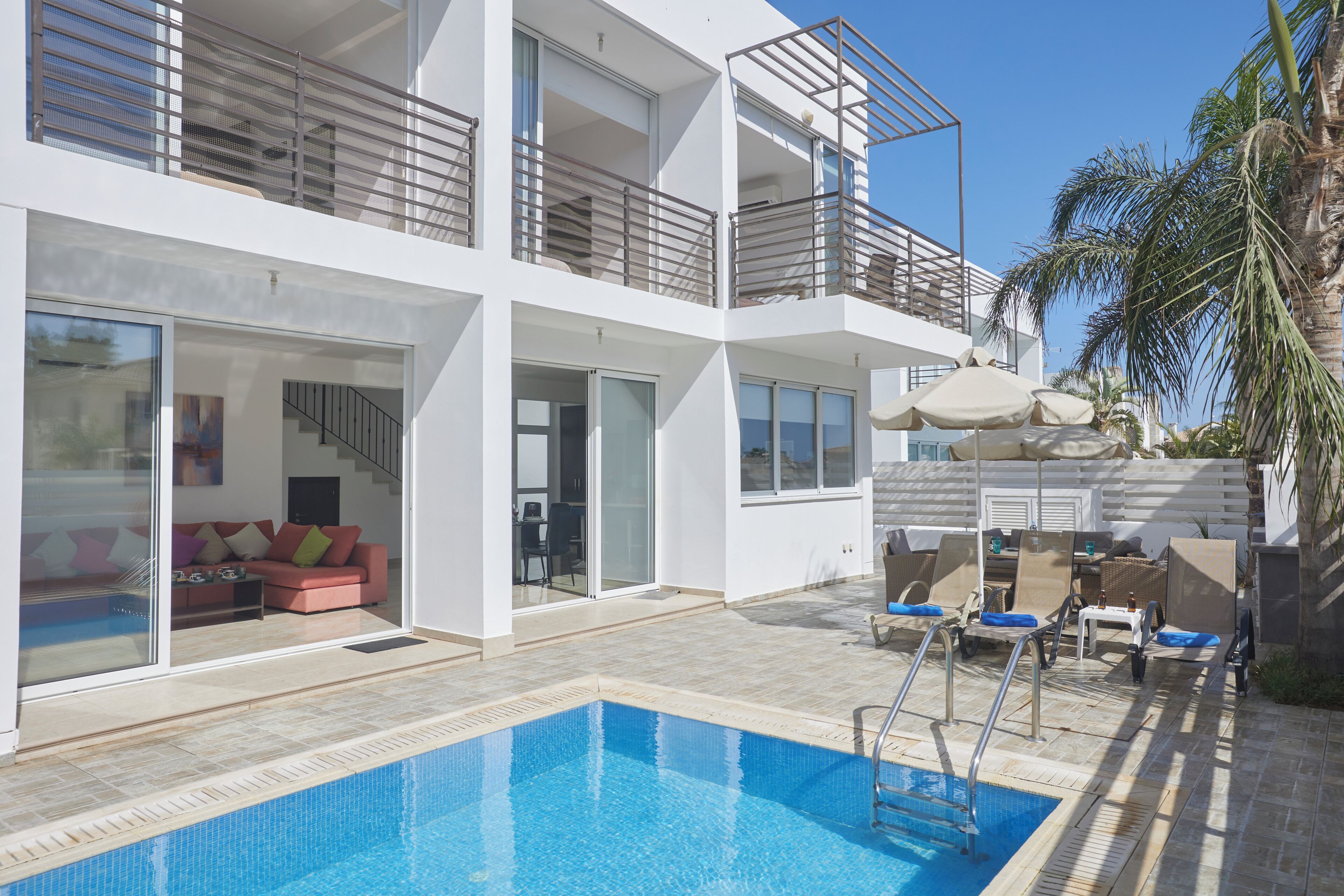 Un immeuble moderne à plusieurs étages, doté d’une piscine, d’un espace extérieur aménagé et d’un escalier menant aux étages supérieurs.