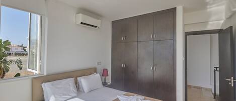 A bedroom with a bed, a wardrobe, and a window.