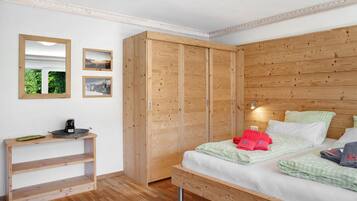 A bedroom with a wooden wardrobe, a bedside table, a bed with green checkered bedding, and two framed pictures on the wall.