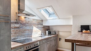 Een moderne keuken met dakraam, roestvrijstalen apparatuur en een houten aanrecht.