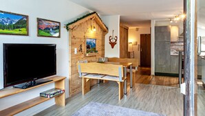 Een moderne woonkamer met een flatscreen televisie, een houten eettafel en een gezellige open haard.