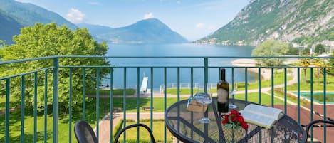 A balcony with a table, a book, a wine glass, and a rose.