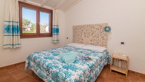 A bedroom with a bed, curtains, a headboard, and a small bedside table.