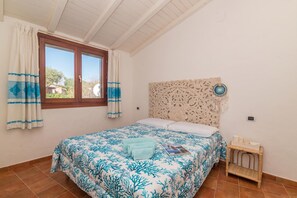 Une chambre à coucher avec un lit, des rideaux, une tête de lit et une petite table de chevet.