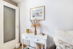 A white console table with a framed picture, a vase with dried plants, a glass jar, and a small wooden box. - Charming "Enz" Apartment in Bietigheim’s Old Town (Bietigheim-Bissingen)