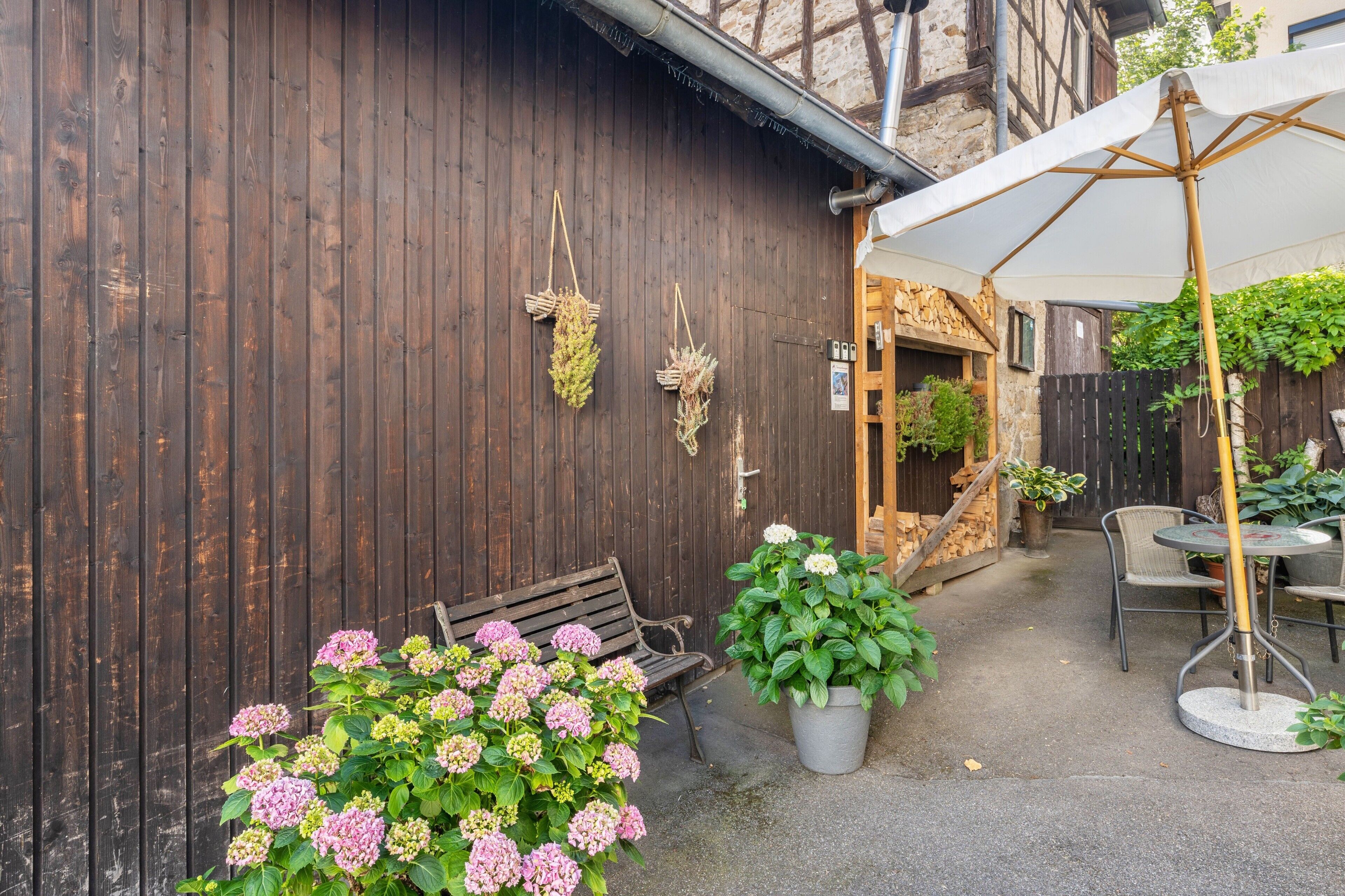 Ein Holzgebäude mit einer Bank und einem Tisch mit Sonnenschirm.