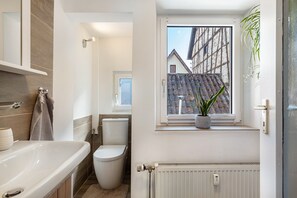 A bathroom with a bathtub, toilet, and a window with a view of a building.