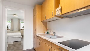 Una cocina moderna con armarios de madera, encimera blanca y placa de inducción integrada.