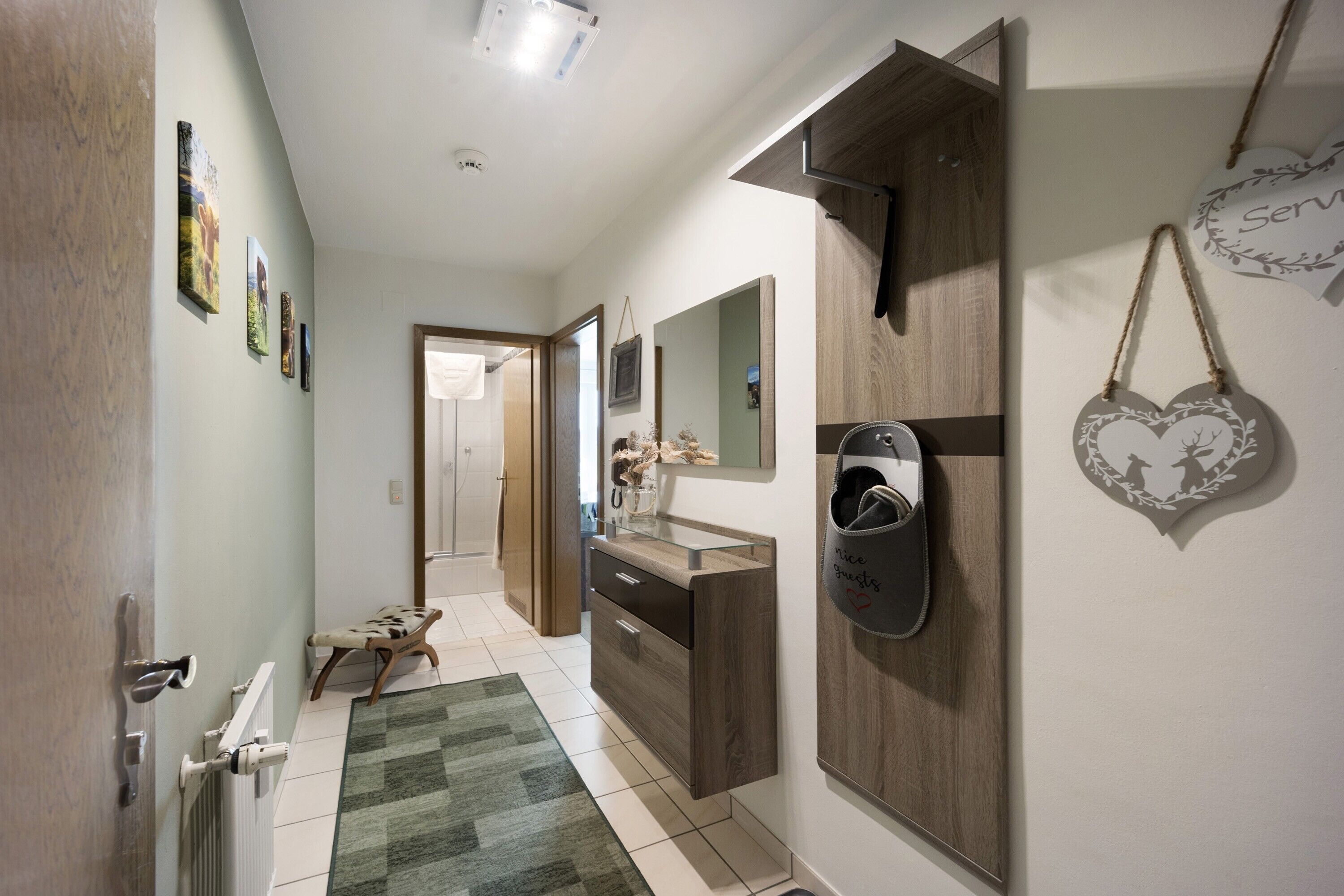 A hallway with a wooden bench, a radiator, a mirror, and a wall-mounted bag rack.