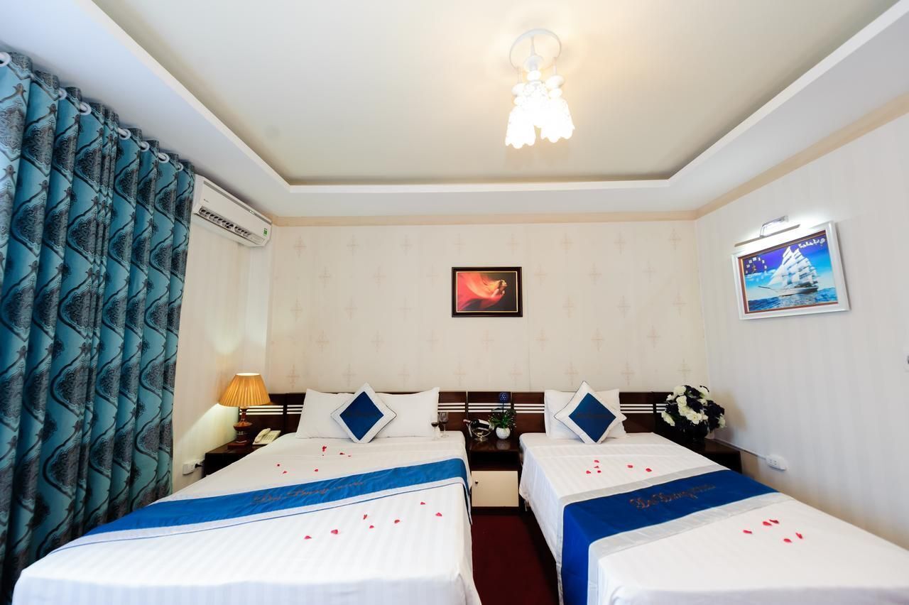 A hotel room with two beds, a ceiling light, a wall-mounted air conditioner, and a framed picture.
