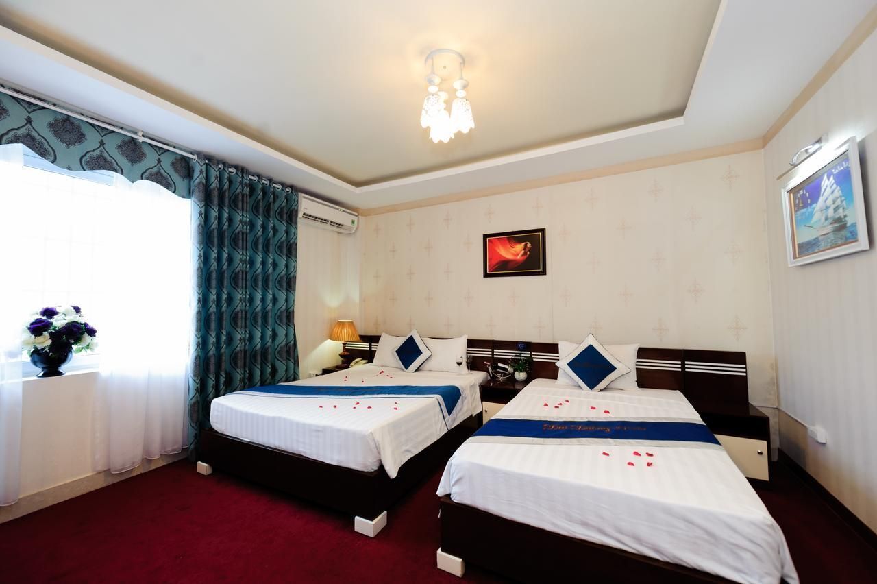 A hotel room with two beds, a chandelier, a window with curtains, a wall-mounted air conditioner, and a framed picture.