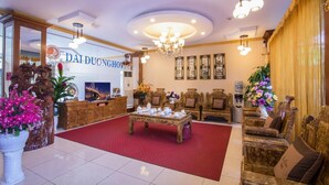 Un hall d’entrée luxueux, avec un tapis rouge, des meubles richement décorés et un lustre.