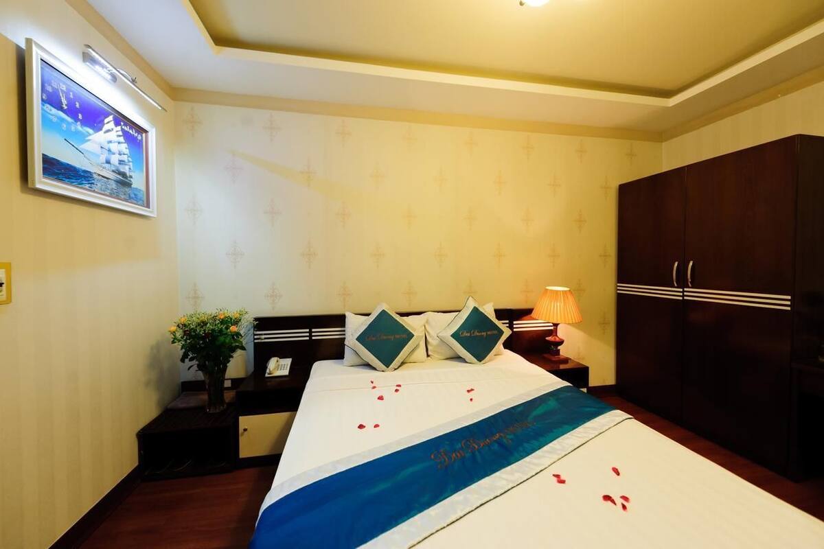 Una habitación de hotel con una cama, una mesita de noche, un televisor y un armario.