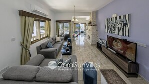 A living room with a sofa, coffee table, TV, and artwork. - Fabulous Villa In Coral Bay Near Beach, Amenities (Peyia)