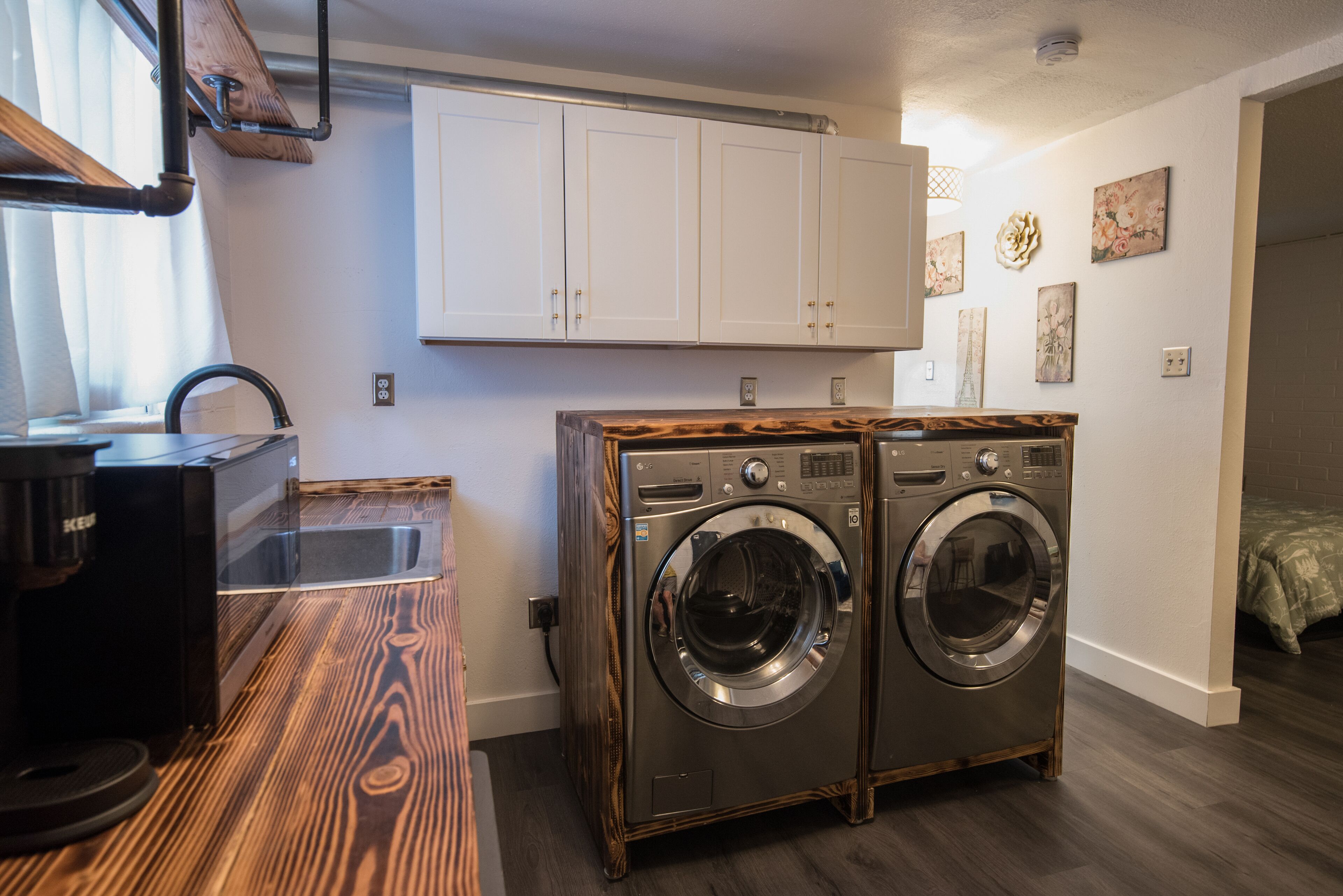 A laundry room with two front-loading washing machines, a sink, and a coffee maker.