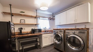 Cocina compacta con refrigerador, microondas, pileta y lavadora.