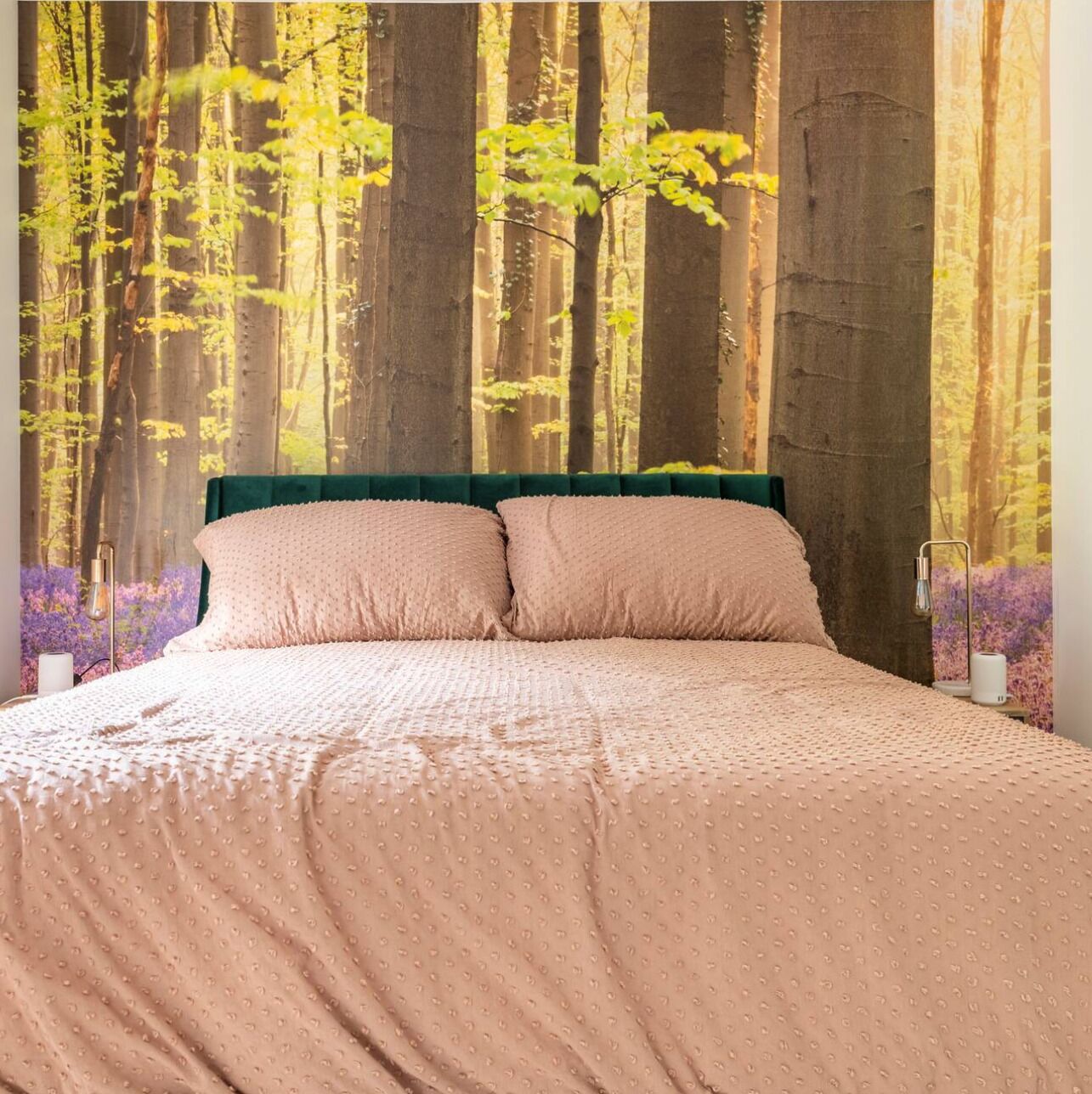 A bedroom with a bed, a green headboard, and a forest wallpaper.