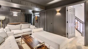 Un salon moderne avec un canapé blanc, une table basse en bois et une grande porte grise.