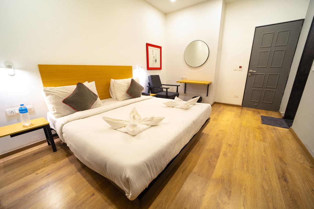Habitación de hotel con cama, una silla, un escritorio y una puerta.