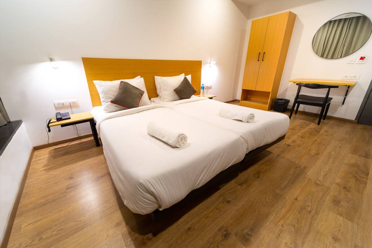 Habitación de hotel con una cama grande, cabecera de madera, mesitas de noche, un escritorio y un espejo.