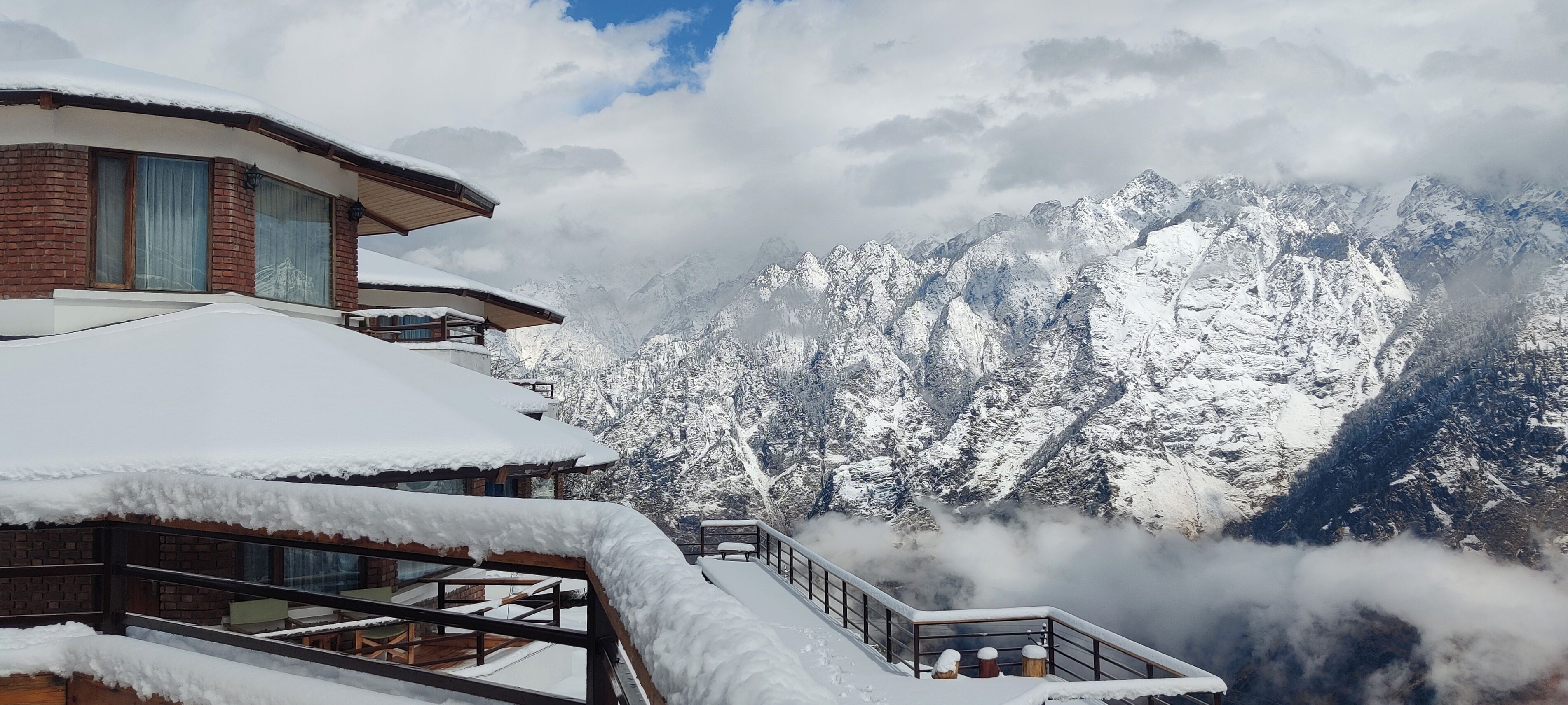 A snow-covered mountain resort with a modern building featuring large windows and a balcony.