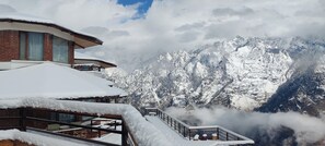 Une station de montagne enneigée, avec un bâtiment moderne doté de grandes fenêtres et d’un balcon.