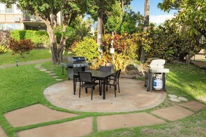 An outdoor patio with a grill, table, and chairs.