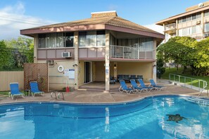 A two-story building with a swimming pool, lounge chairs, and a lifeguard station.