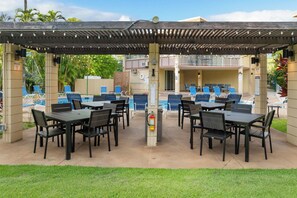 An outdoor pool area with multiple seating arrangements and a covered section.