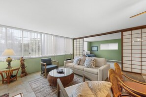 A living room with a sofa, armchairs, a coffee table, and a dining table.