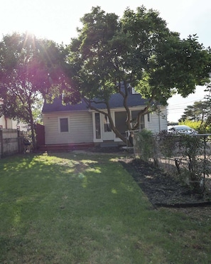 A residential house with a front yard, a tree, and a car parked in the driveway.