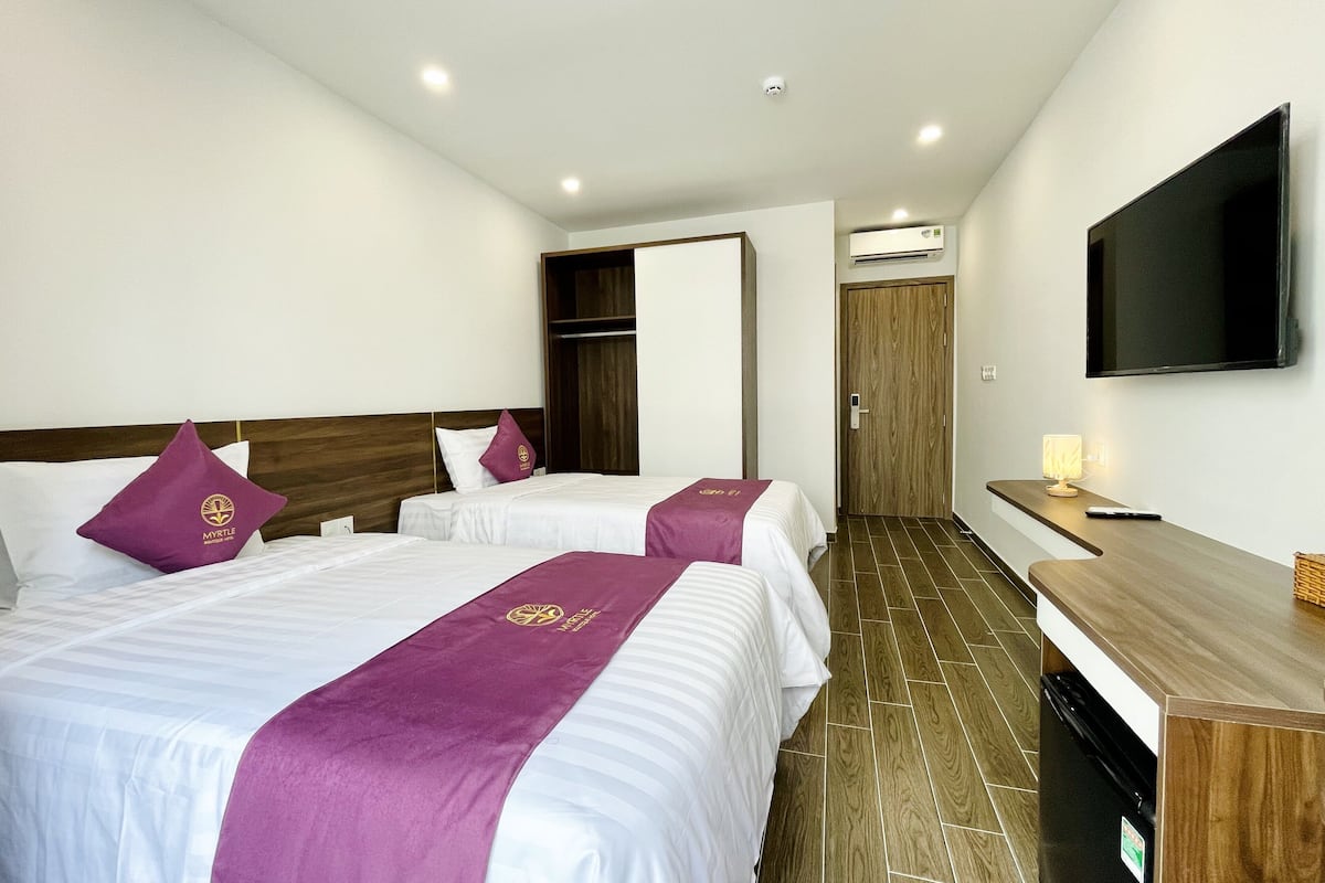 A hotel room with two beds, a TV, a desk, and a wardrobe.