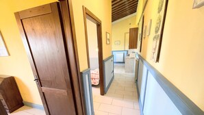 A hallway with wooden doors, a tiled floor, and a kitchen area in the distance. - Apt 5 Aircon, Wifi, Infinity Pool, Jacuzzi, Gardens Incredible! Sleeps 4 (Spoleto)