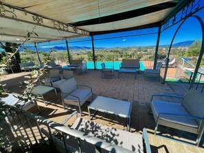 Une terrasse extérieure aménagée avec des meubles en osier et offrant une vue sur un paysage montagneux.