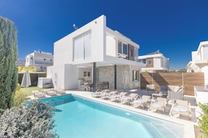 A modern two-story house with a swimming pool, outdoor seating, and a visible restaurant.