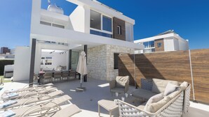 A modern outdoor living area with lounge chairs, a dining table, and a stone wall.