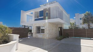 A modern two-story house with a stone facade, a balcony, and a clear sky.