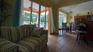 A living room with a striped sofa, a dining area with chairs, and a kitchen area with cabinets. - Las Brisas, Juan Dolio, 3br, 2 Pools, Jacuzzi, Beach, Golf, 7 Sleeps (Guayacanes)