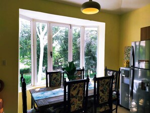 Enjoy meals with a view of the lush outdoor space from this dining area featuring a wooden table and chairs.