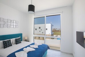 A modern hotel room with a large bed, a view of the outdoors, and a flat-screen TV. - Protaras Vie Bleu Villa Vb5 (Paralimni)