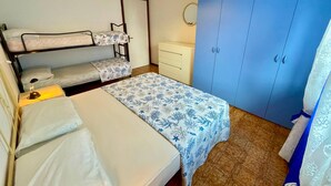 A room with bunk beds, a desk, a wardrobe, and a hanging light fixture.